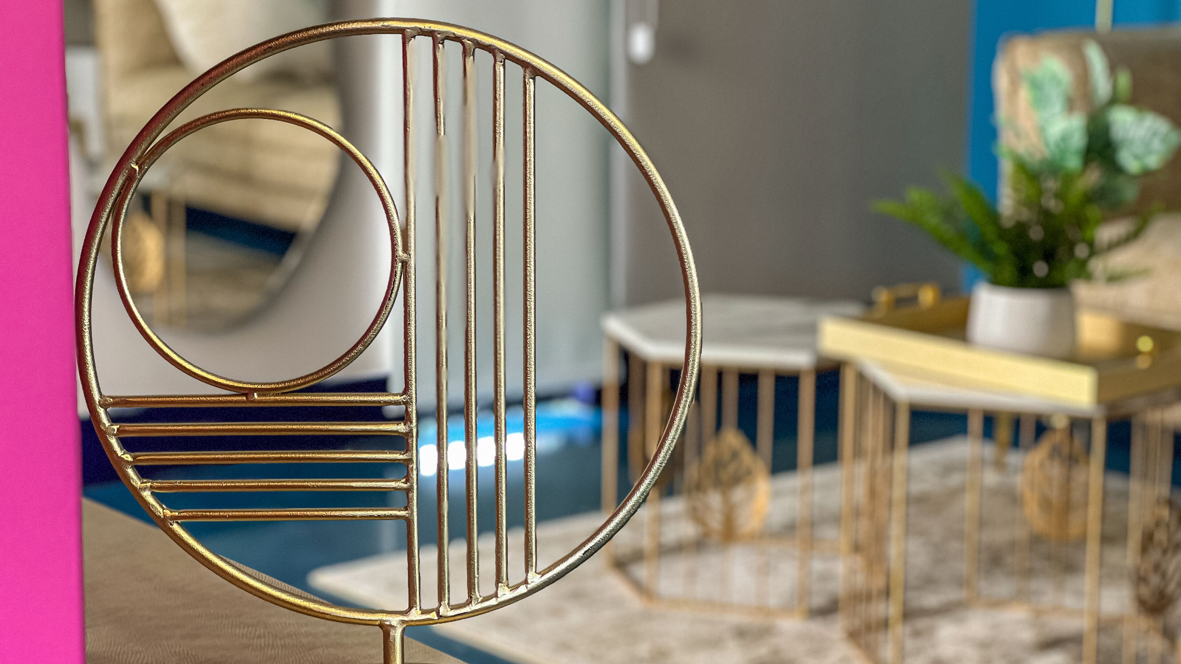 Ein modernes Interieur mit einem runden Metallstuhl, einem kleinen Tisch und einer Topfpflanze.