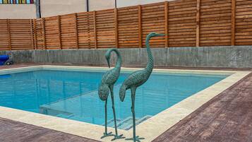 A swimming pool with two decorative swan statues.