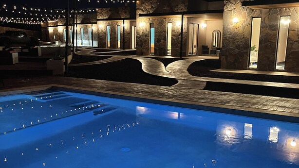 Una piscina con cubierta de piedra y un edificio de piedra al fondo, con varias puertas y ventanas.
