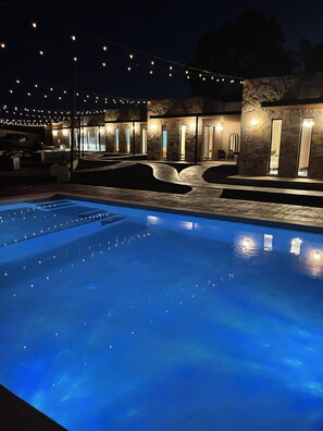 Una piscina con cubierta de piedra y un edificio de piedra al fondo, con varias puertas y ventanas.