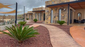 Un espacio exterior moderno con muros de piedra, un sendero y mobiliario para estar al aire libre.