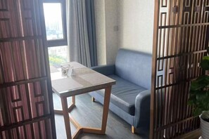 A room with a sofa, a table, and a view through a window. - Lihao Hotel (Chongqing Yongchuan High-speed Railway Station) (Chongqing)