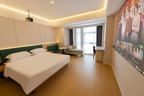 Habitación de hotel con una cama grande, un escritorio, una silla y un televisor montado en la pared.