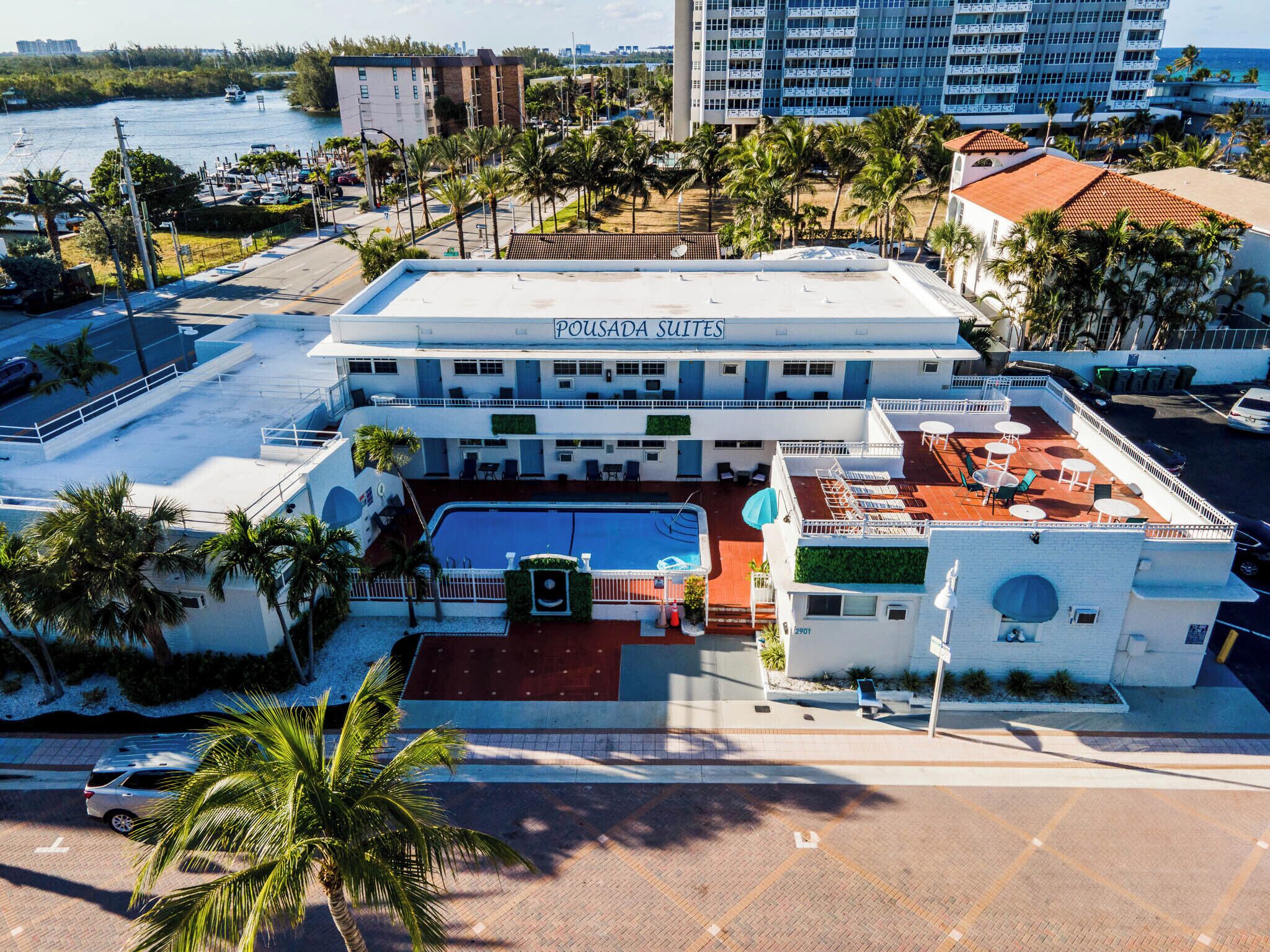 A hotel with a rooftop pool, outdoor seating, and a view of the water.