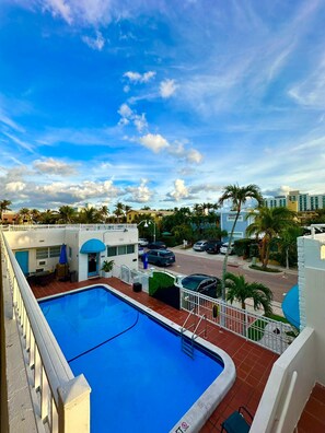 A swimming pool with a view of a parking area and palm trees. - Pousada Suites at Hollywood Beach (Hollywood)