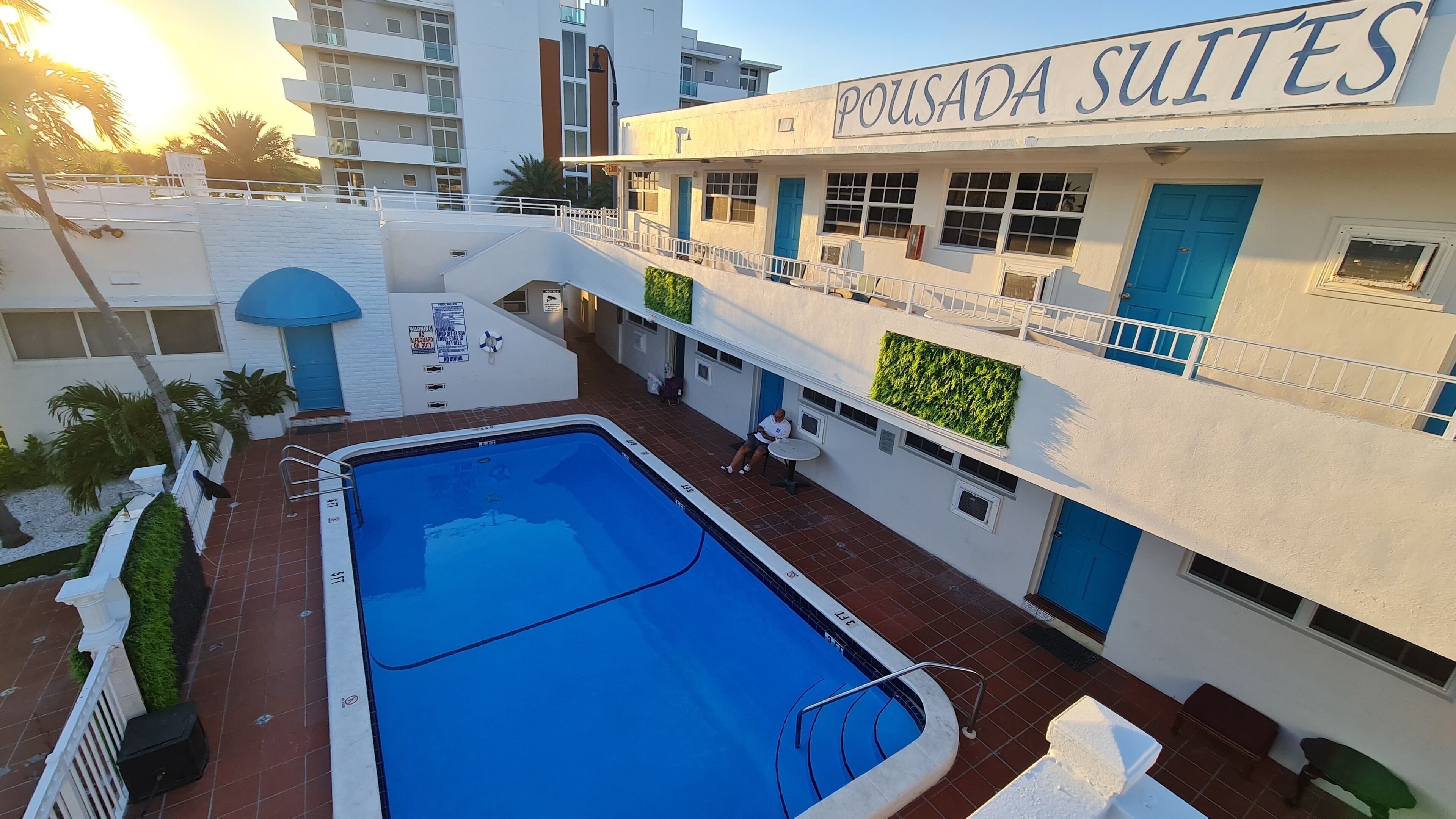 A hotel with a swimming pool, outdoor seating, and a sign reading "POUSADA SUITES".