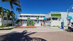 A hotel with a modern design, featuring a prominent 'Pousada Suites' sign, a gated entrance, and a parking area. - Pousada Suites at Hollywood Beach (Hollywood)