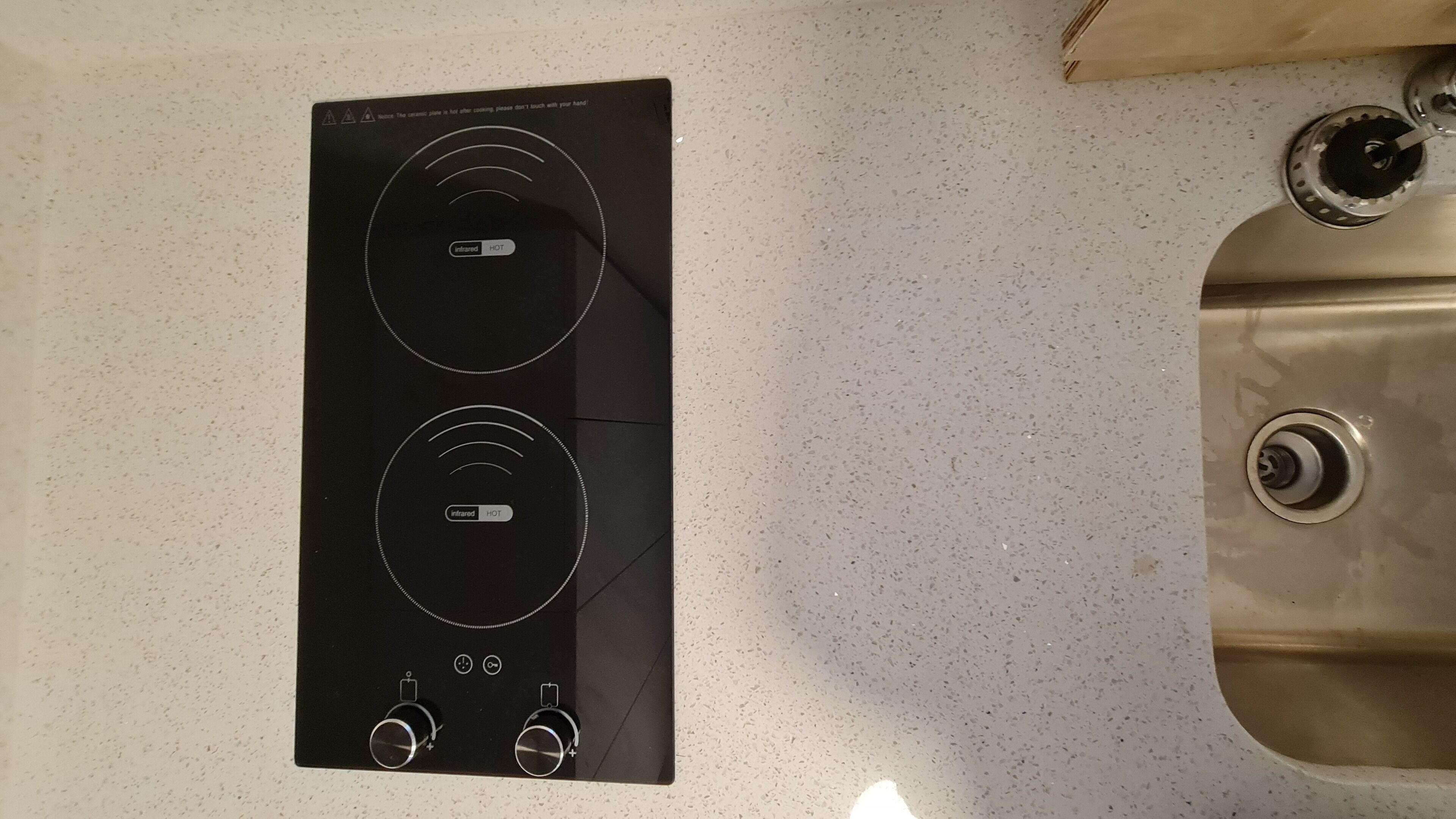 Eine Küche mit einem schwarzen Induktionskochfeld und einer Spüle aus Edelstahl.