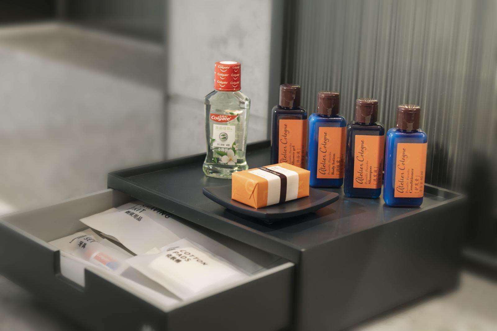 A toiletry station with a bottle of colgate, several bottles of cologne, and a bar of soap.