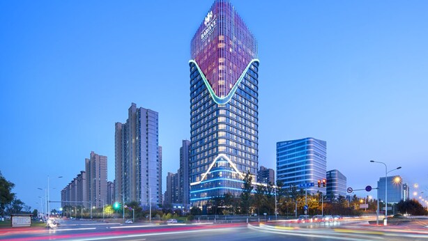 Un immeuble moderne de grande hauteur, doté d’une architecture originale aux lignes courbes, et entouré d’autres immeubles de grande hauteur dans un environnement urbain.