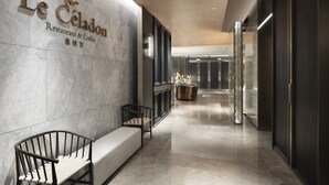 Un intérieur moderne comprenant un comptoir d’accueil, un espace salon et un mur orné du nom du restaurant.