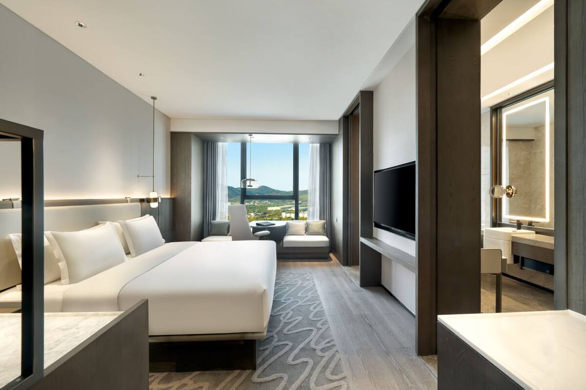 Een moderne hotelkamer met een groot bed, een televisie, een bureau en een badkamer met een spiegel.