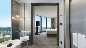 Une chambre d’hôtel moderne dotée d’un grand lit, d’une télévision et offrant une vue sur le paysage urbain.