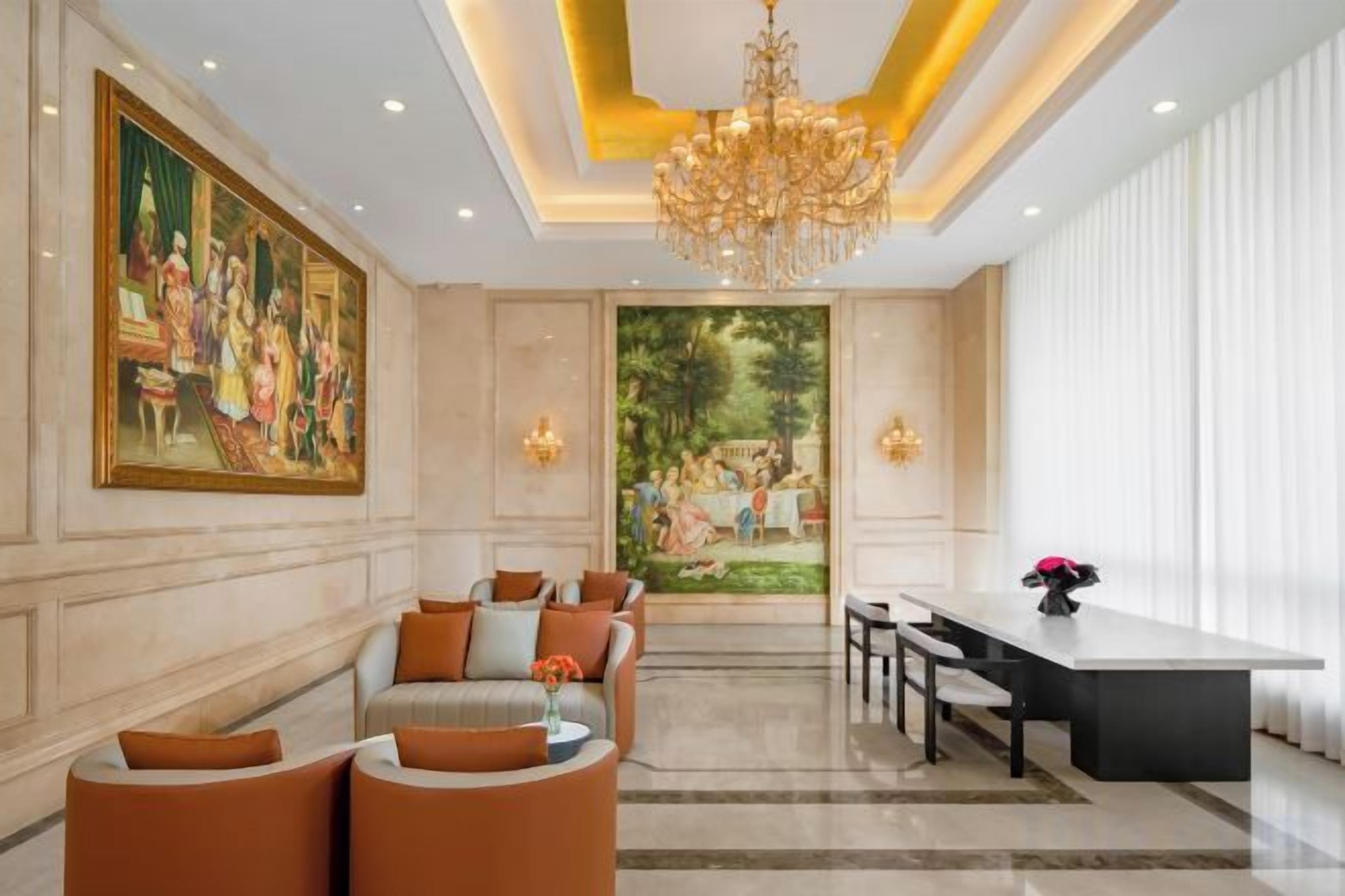 A hotel lobby with a chandelier, seating area, and a painting on the wall.