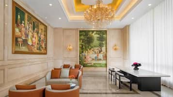 A hotel lobby with a chandelier, seating area, and a painting on the wall.