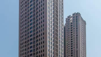 Two high-rise buildings with a grid of windows and a clear sky in the background.