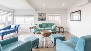 A spacious living room with a teal sofa set, a blue sofa, and a round coffee table. - 80 Feet of Private Lakefront House (Amherstburg)