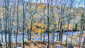 A wooden staircase leading to a bridge over a river, surrounded by trees and autumn foliage. - Cozy King Bed Studio - Mtn Views - Direct River Access in back (Lincoln)