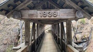 A wooden pedestrian bridge with a sign reading "Sentinel Pine Bridge 1939" and a year marker "1984".