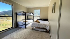 Ein Schlafzimmer mit Etagenbetten, einem großen Fenster und Blick auf eine Landschaft.