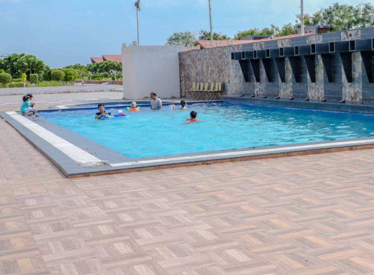 A swimming pool with tiled flooring and a stone wall with windows.