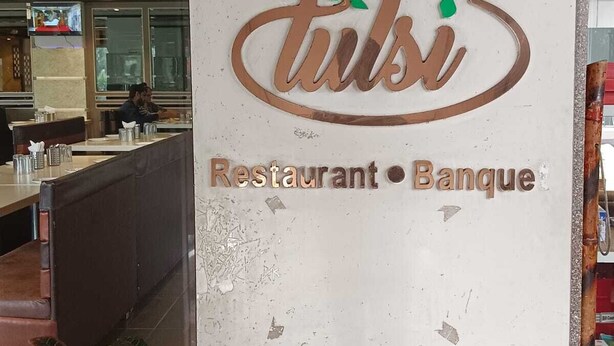 A restaurant and bank sign with the name 'tulsi' and a logo with green leaves. - Hotel Tulsi (Surat)