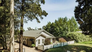 A single-story house with a fenced yard, surrounded by trees.