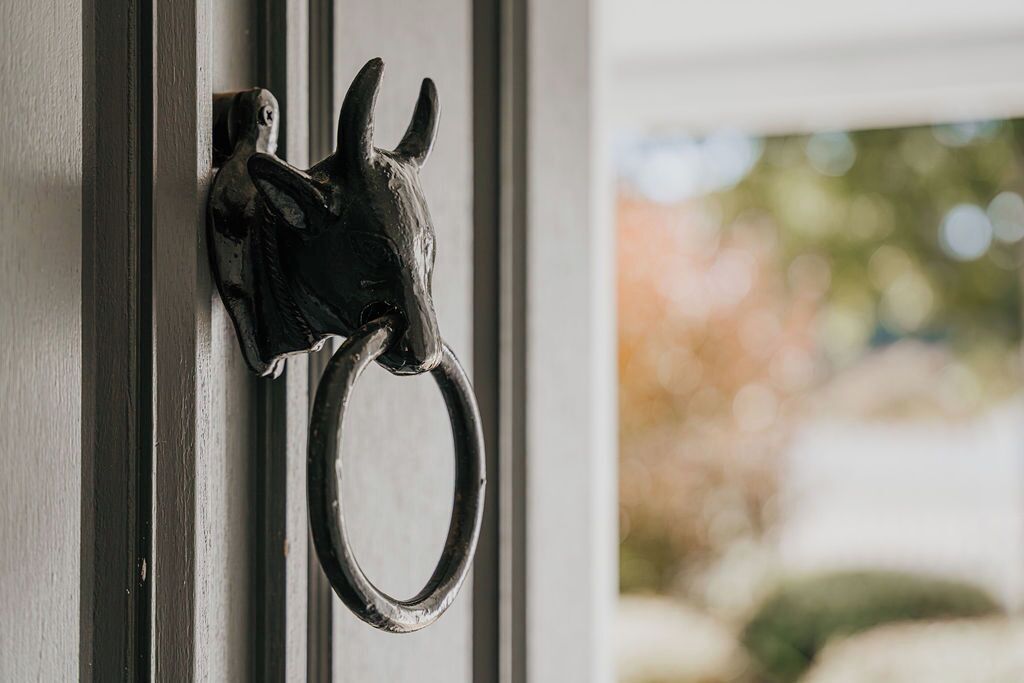 A metal door knocker shaped like a goat's head.