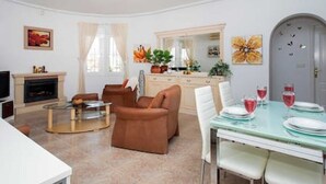 Ein modernes Wohnzimmer mit Sofa, Couchtisch und Esstisch, gedeckt für eine Mahlzeit.