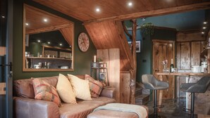 A cozy living area with a leather sofa, a wooden coffee table, and a large mirror. - Tawny Lodge - 1 Bedroom - Blossom Farm (Haverfordwest)