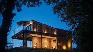 A modern two-story house with a balcony, large windows, and a wooden exterior. - Tawny Lodge - 1 Bedroom - Blossom Farm (Haverfordwest)