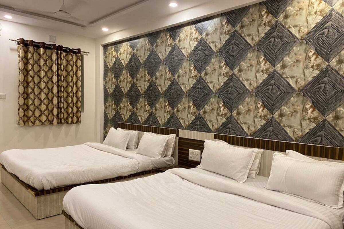 A hotel room with two single beds, a patterned wall, and a curtain.
