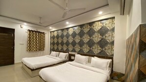 Une chambre d’hôtel avec deux lits, un ventilateur de plafond et un papier peint à motifs.