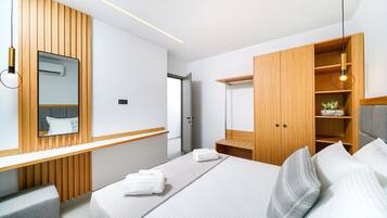 A modern hotel room with a large bed, a wooden wardrobe, a bedside table, and a mirror.