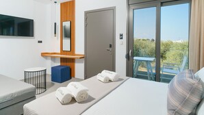 Une chambre d’hôtel moderne équipée d’un lit, d’un bureau, d’une chaise, d’une télévision et d’un balcon avec vue.