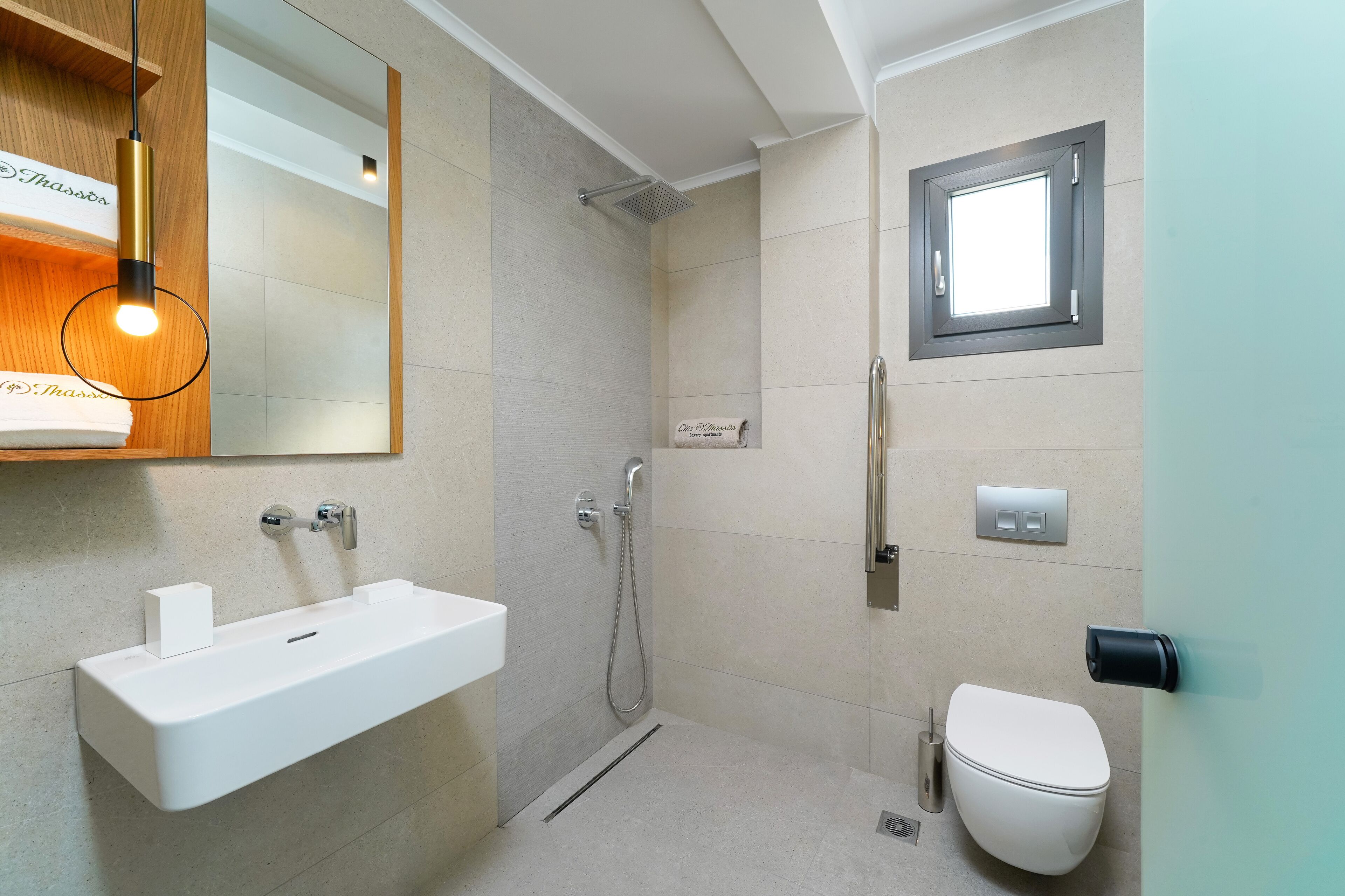 A modern bathroom with a white sink, a shower, and a toilet.