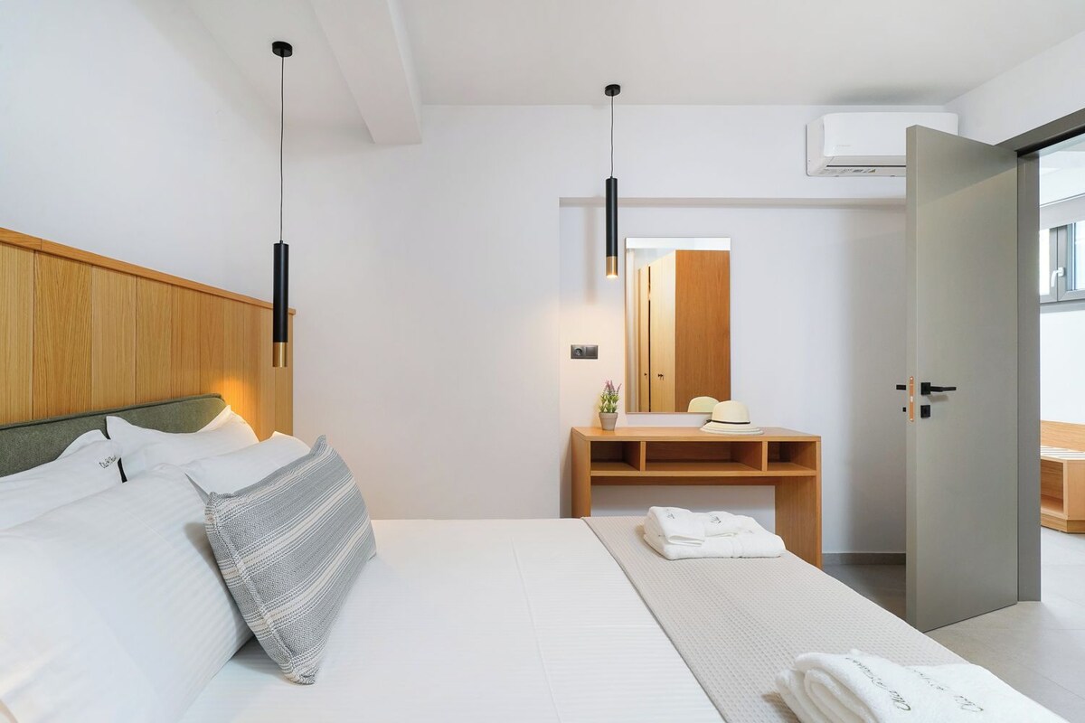 Ein modernes Hotelzimmer mit Bett, Nachttisch, Spiegel und Blick ins Freie.