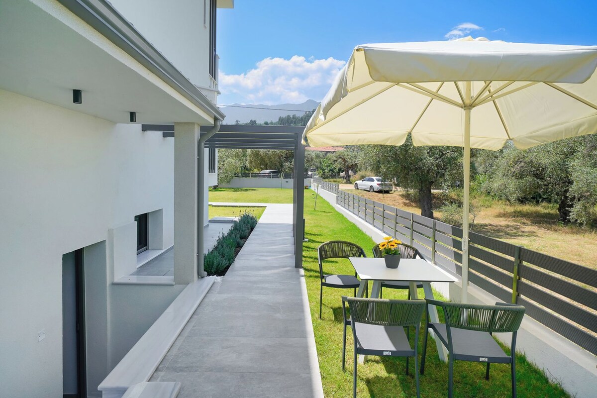 Une terrasse extérieure moderne, dotée d’une table et de chaises, d’une pergola et d’un grand parasol.