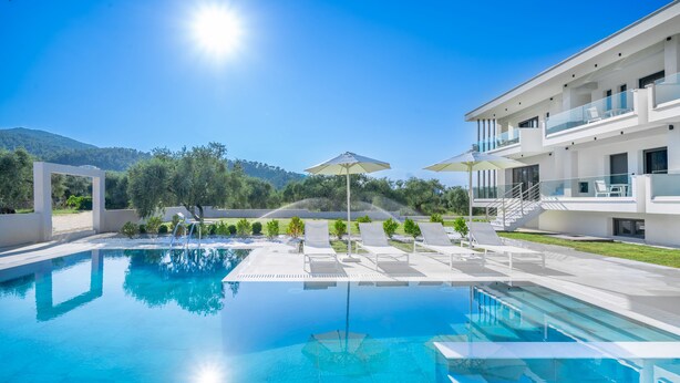 Un espace piscine moderne avec une eau d’un bleu limpide, des parasols et des chaises longues.
