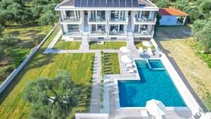 Un grand bâtiment moderne à deux étages, doté d’une piscine, entouré de pelouses et d’arbres bien entretenus.