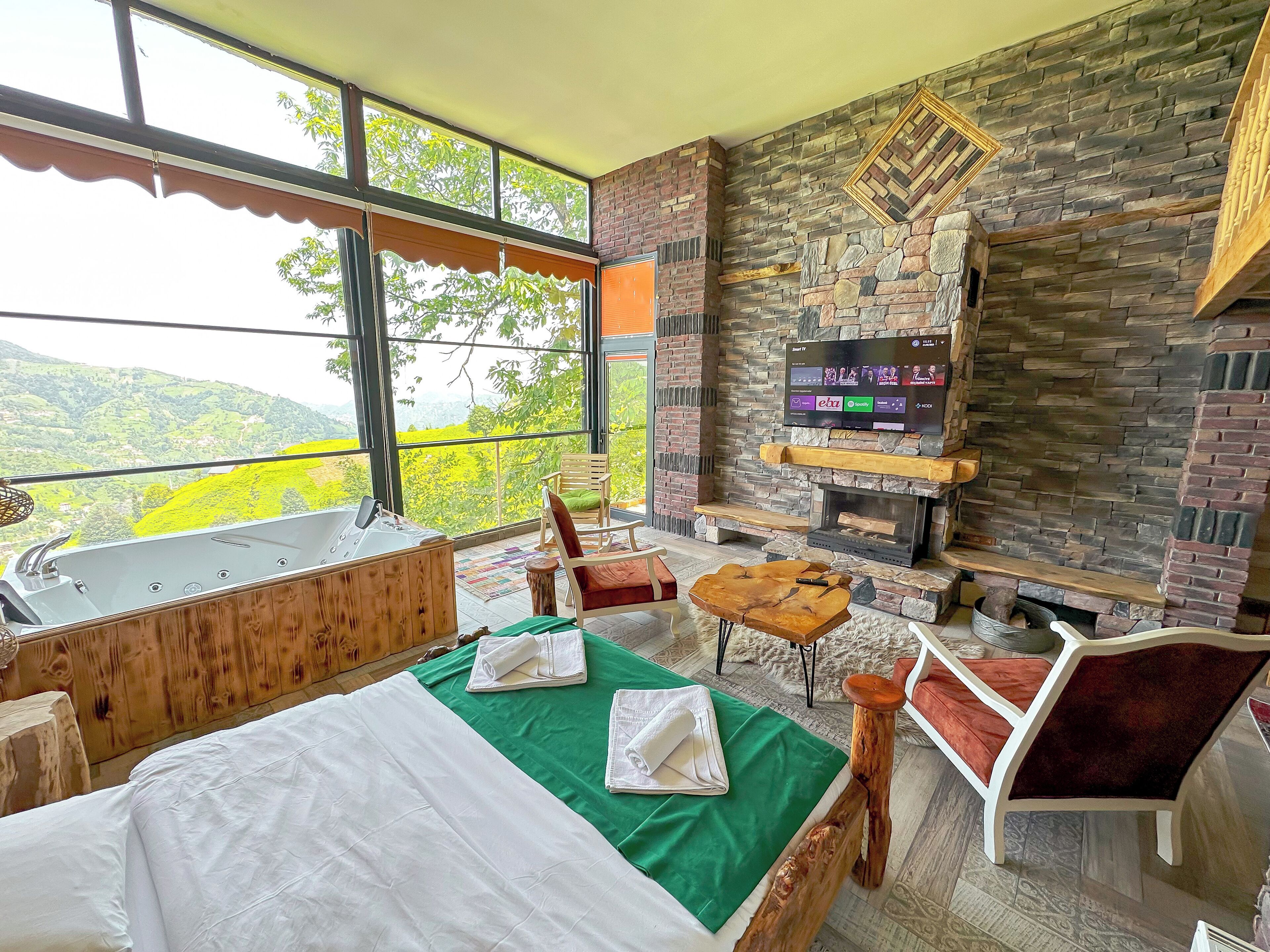 A room with a bed, a wooden tub, a fireplace, and a TV.