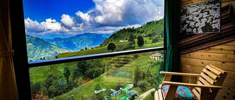 Una habitación con un gran ventanal que ofrece vistas a colinas verdes y un cielo azul.
