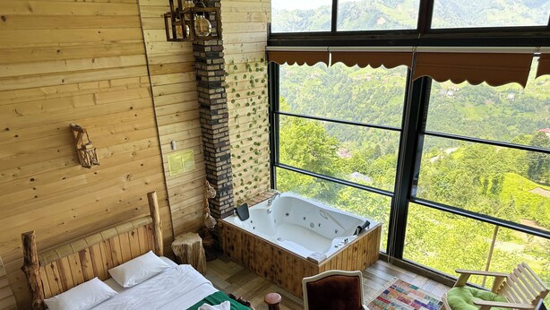 Une pièce de style cabane en bois, avec une grande fenêtre, un lit en bois, une chaise en bois et une baignoire.