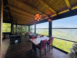 Una terraza de madera con una mesa y sillas, una chimenea y vistas del paisaje.