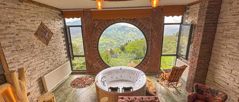 Un dormitorio con un ventanal circular grande, una bañera, una cama y una silla.