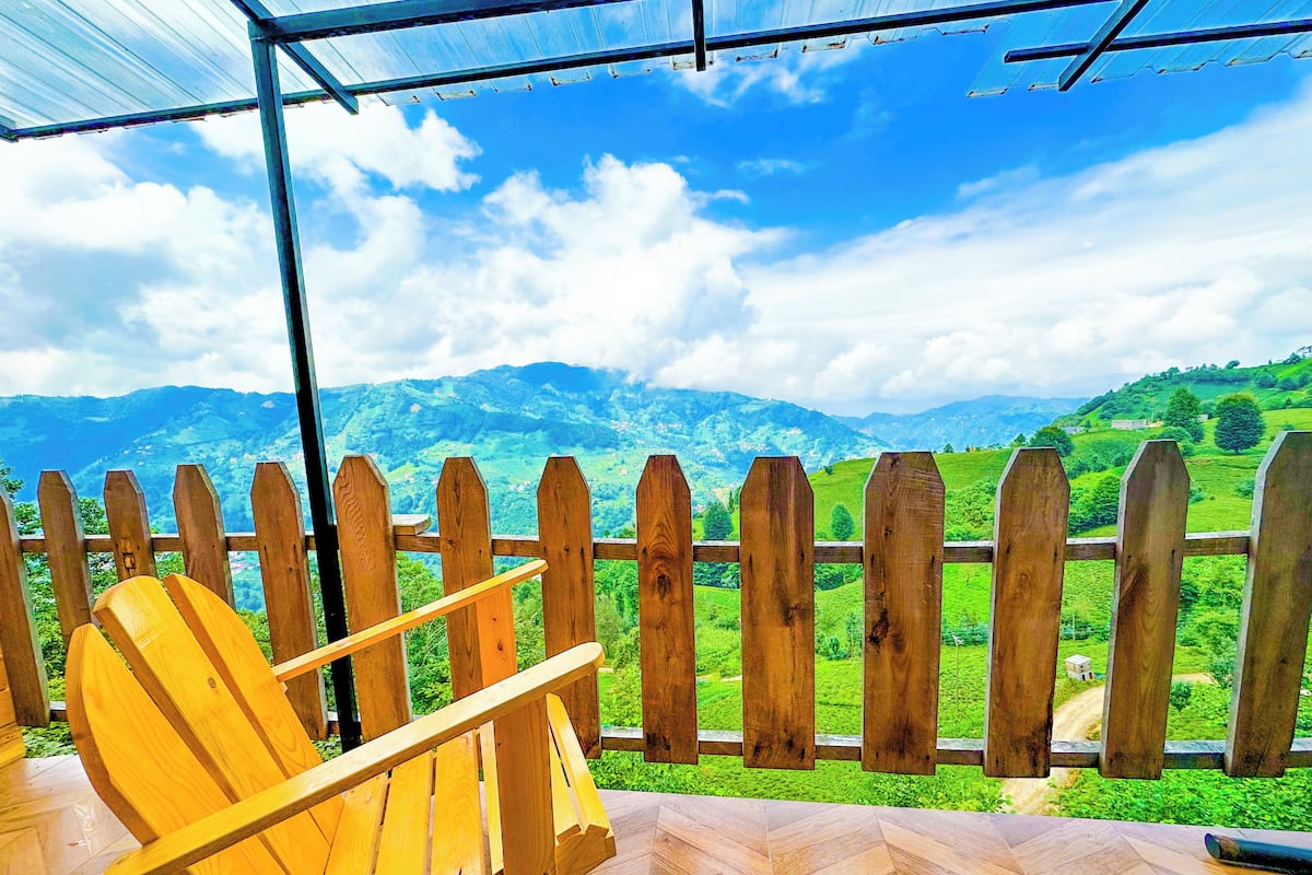 A wooden chair and a wooden fence overlooking a mountainous landscape.