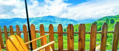 A wooden chair and a wooden fence overlooking a mountainous landscape.