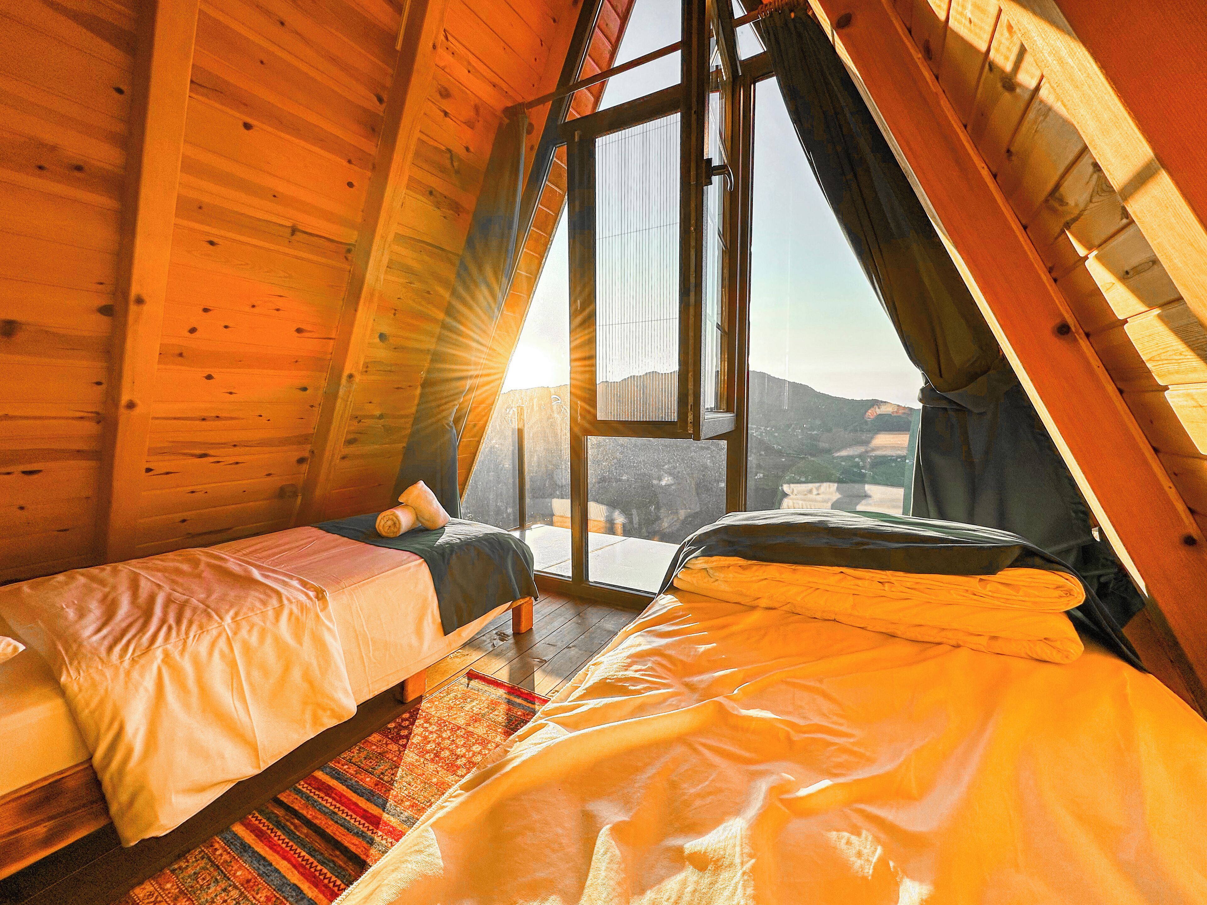 Un dormitorio acogedor en el ático con dos camas, un ventanal grande y vistas al paisaje.