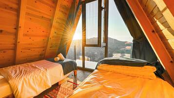 Un dormitorio acogedor en el ático con dos camas, un ventanal grande y vistas al paisaje.