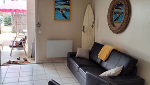 Ein Wohnzimmer mit einem schwarzen Ledersofa, einem Holztisch und einem an der Wand befestigten Surfbrett.